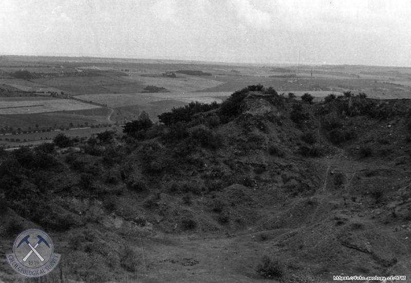 Fotografie : Star� velk� severn� lom. Uprost�ed allothigenn� p�s�it� tuf s mal�m proudem �edi�e, pod n�m tmav�� p�s�it� tufity. Vlevo �edi�ov� p��krov. Olivinick� nefelinit., Vina�ick� hora